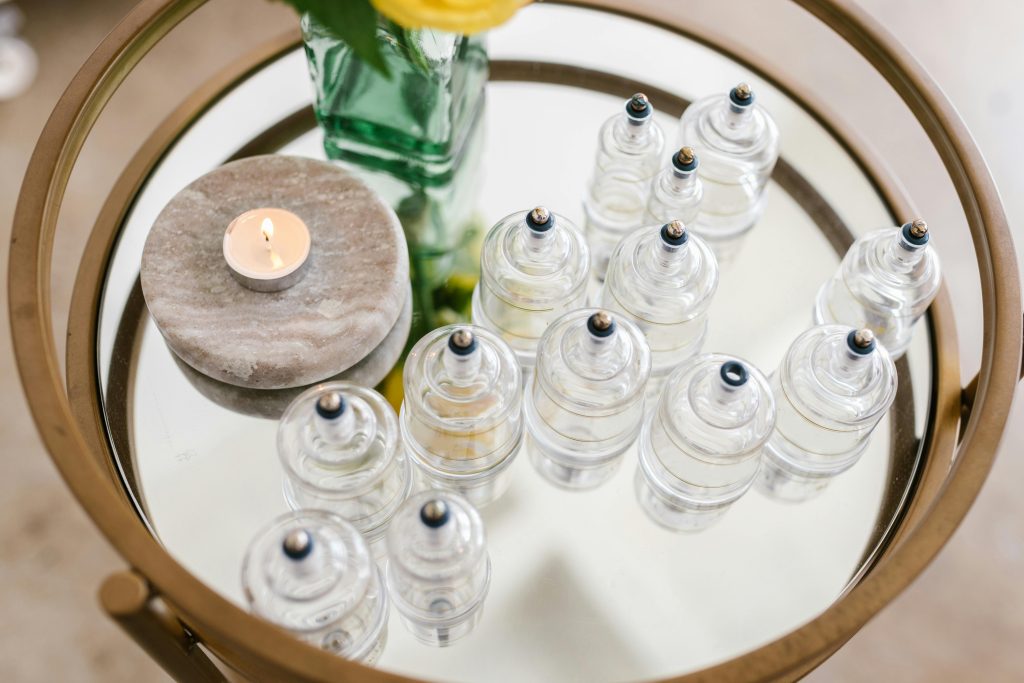 pexels photo 8312798 8312798 A stylish arrangement of glass cupping jars on a mirrored table with a candle and flowers, ideal for spa settings.